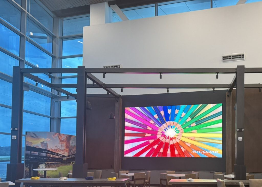 Large wall-mounted display showing a color test image above a seating area.